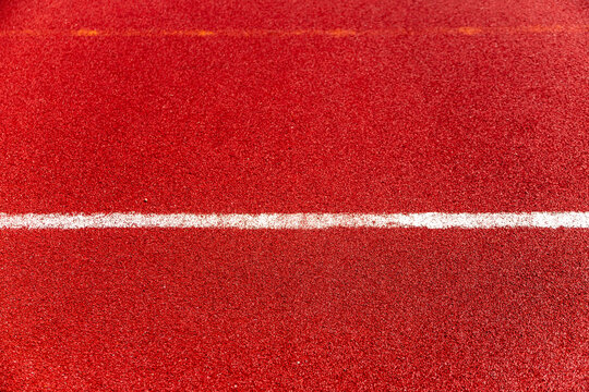 Red stadium track surface with white football field line
