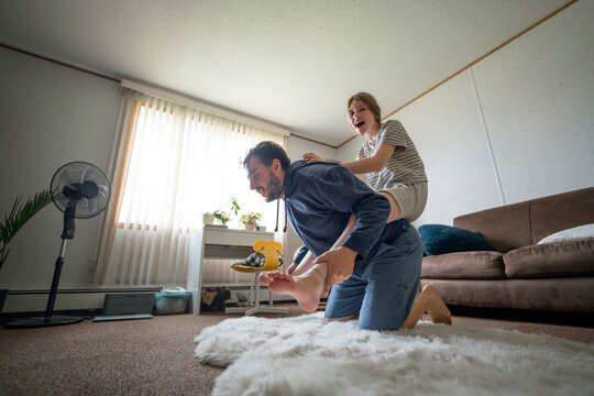Father gives daughter a playful piggyback ride at home