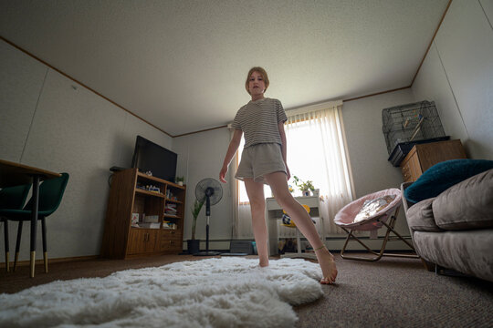 Young girl stands barefoot in a bright living room