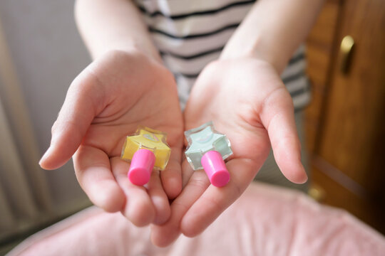 Girl holding colorful nail polish bottles in open hands