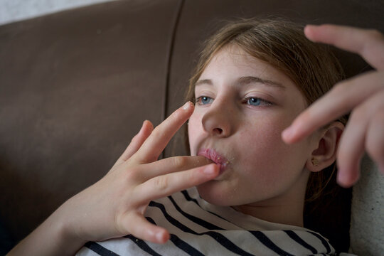 Girl lick finger while relax on sofa at home