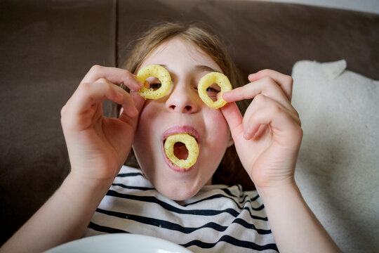 Girl play with snack ring as funny face at home
