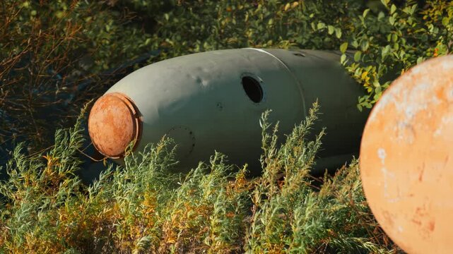Obsolete, abandoned, and rusty combat missiles and shells stand amidst the natural landscape. A weapons graveyard. An echo of war.