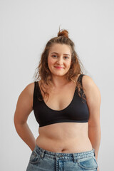 Woman in black top stands calmly and smiles without hiding her figure, confidence built after thirty five years, story many women recognise. Wide shot. Concept of body confidence after thirty five © iwavephoto