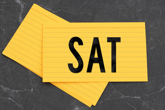 SAT text on a bright yellow index cards on black stone