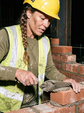 Mason apply mortar to brick wall construction work