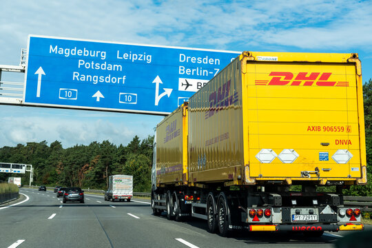Germany - Aug 22, 2026: Yellow DHL road train passing under blue direction boards for Magdeburg, Leipzig, Potsdam, Rangsdorf, Dresden and Berlin with cars and a lorry in the other lanes
