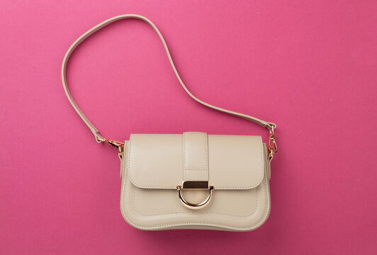Woman leather bag on color background, top view