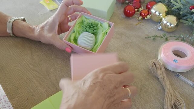 Woman preparing and wrapping a small christmas gift box