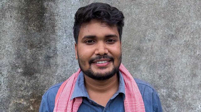 Young indian farmer smiling and standing against plain grey background