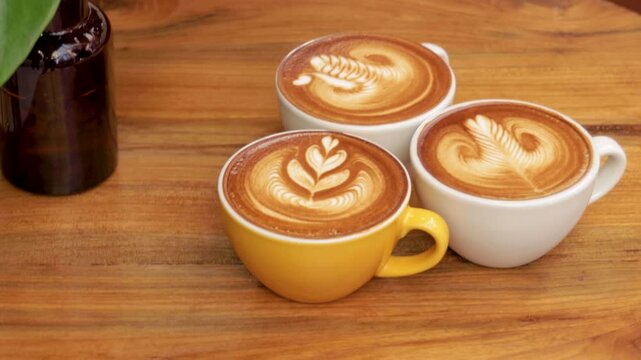 Three Cups of Latte Art Coffee on a Wooden Table