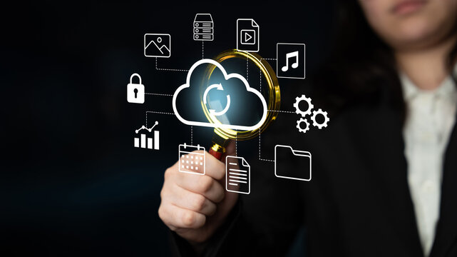A business professional examines cloud computing icons and data management symbols with a magnifying glass, illustrating technology analysis and innovation. Gantry