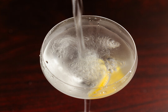 Pouring a classic Vesper Martini in to a martini coupe glass with a slow shutter speed showing motion.