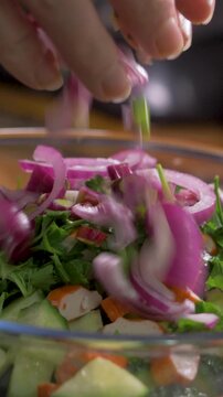 Chopped purple onion mixes with seafood sticks, cucumber cubes and parsley. Preparation of fresh salad, clean food and healthy daily habit with natural ingredients and savory flavor