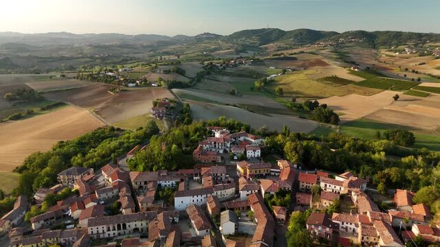 Small Italian village surrounded by golden fields and rolling hills in Piedmont, Italy
