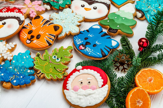 Close up shot of Christmas cookies with icing decorations. Angled macro view of glazed gingerbread shapes, Santa Claus face, tiger, fir twig, orange slice.