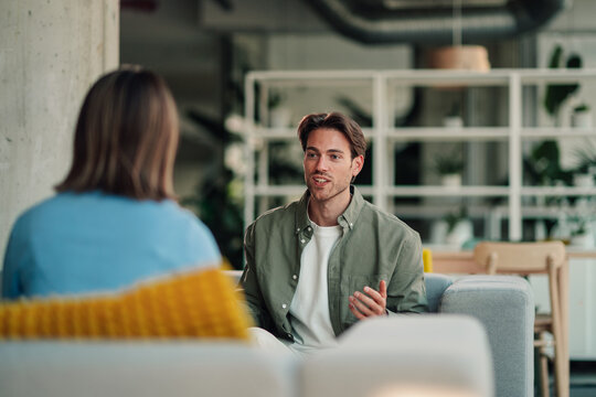 Young man explaining strategy to a woman, having a casual business meeting in a contemporary workspace