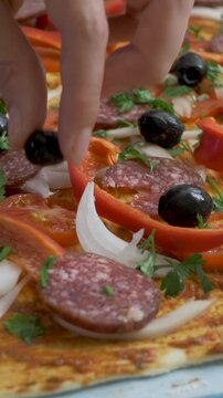 Fresh parsley, sausage, pepper, onion and tomato combine with black olives on dough base. Olive pieces provide bold contrast and savory depth as homemade pizza preparation takes shape