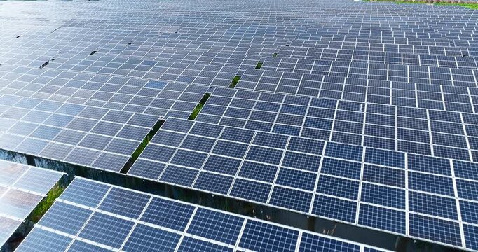 High angle shot of a massive solar panel array installed over water, displaying grid patterns under natural bright sunlight.
