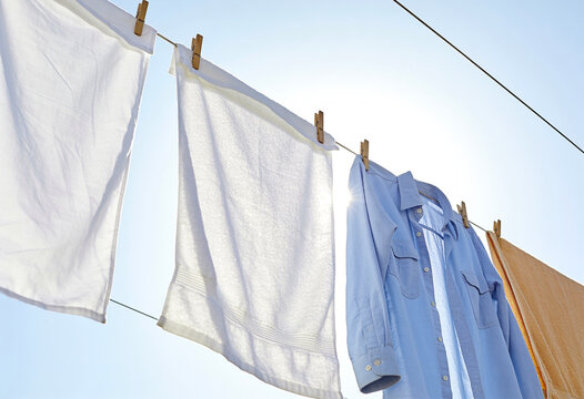 Backlit laundry drying on a line against a bright open sky
