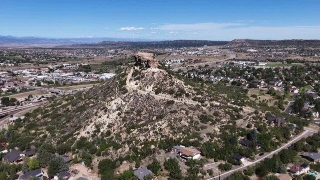 Aerial of prominent hill overlooking Castle Rock residential area in Colorado with scrub brush covering the natural bluff