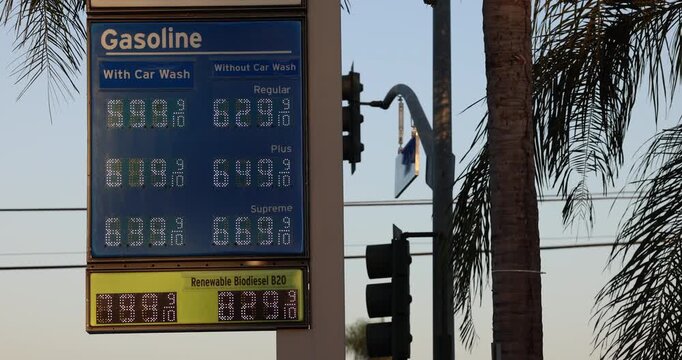 High gas prices display on a board at a gas station on a city street.