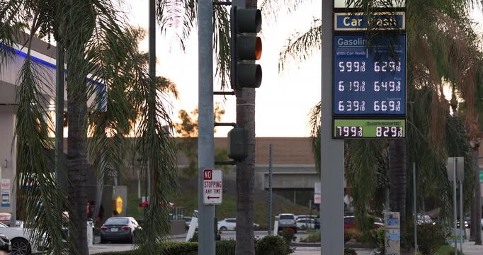 High gas prices display on a board at a gas station on a city street.