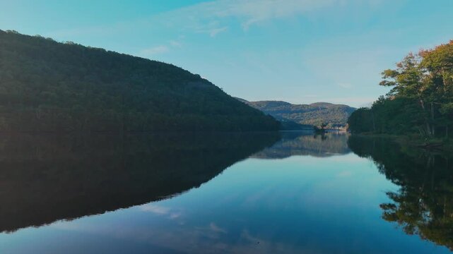 Calm water view at Sherman Reservoir Boat Launch, Vermont, USA, with forested mountains, tree reflections and clear sky. Peaceful nature and boating recreation. 4K.