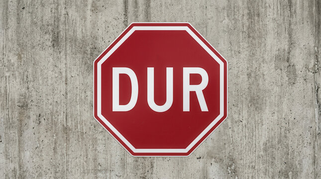 Red Stop Sign With The Word Dur On Concrete Wall Background