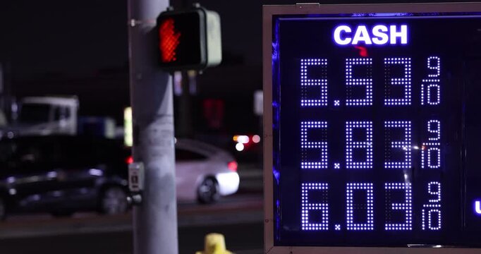 High gas prices display on a board at a gas station on a city street.