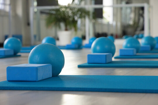 Small blue stability ball and foam block are resting on blue mat in pilates studio