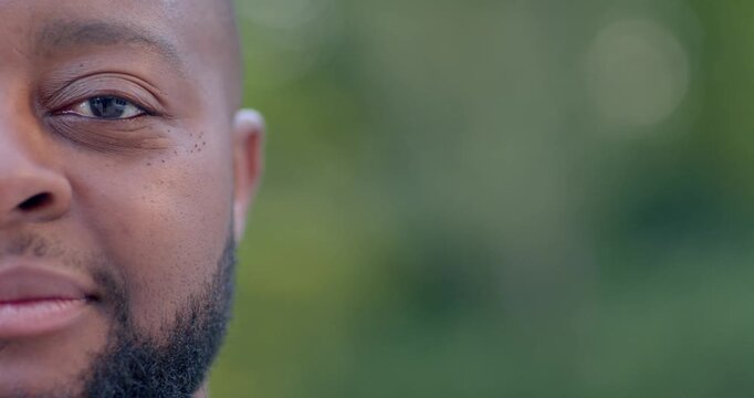 African man smiling and laughing after hearing funny clip on white earbud in park, copy space
