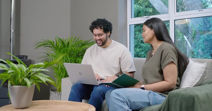 African couple opening laptop, reviewing green folder with pen and typing on couch, planning budget