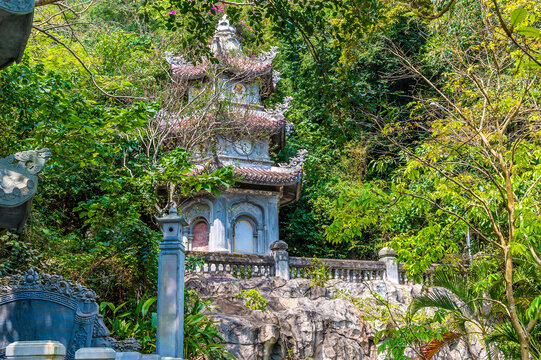 A view towards a pagoda nestled in greenery at the Marble Mountains in Da Nang, Vietnam on a bright sunny day