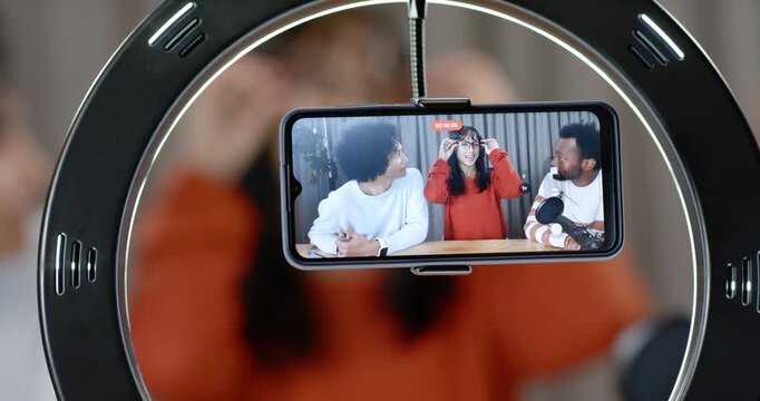 Diverse hosts seeing phone record light center host fixing specs others speaking into mic ringlight
