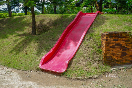 Playground slide with green grass in morning,Empty Outdoor playground,Children Play area in park or garden,Play yard,equipment,School yard, concept.