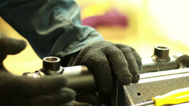 Close up gloved hands assembling hydraulic cylinder vise. Mechanic workshop job.