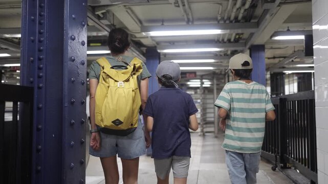 Mother and two sons walking through a new york city subway station corridor, a family exploring the urban environment and using public transportation for commuting