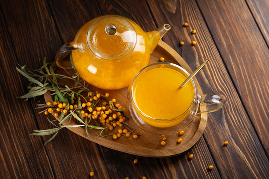 Warm sea buckthorn tea in glass teapot and cup with berries on wooden tray warm drink beverage refreshment concept