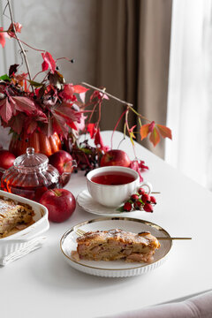 Autumn harvest table setting featuring apple pie slice with warm tea and vibrant red foliage for seasonal enjoyment