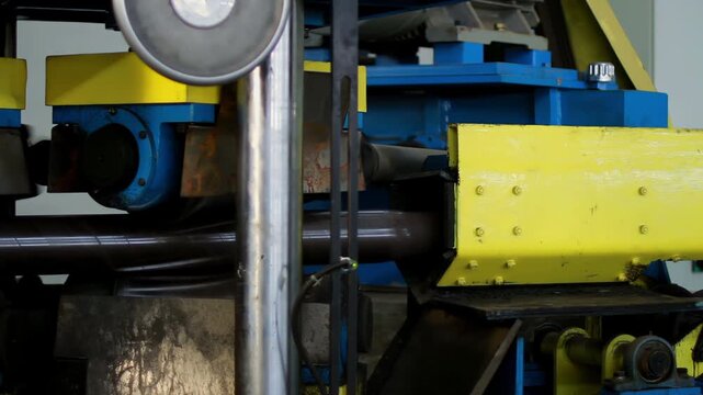 Steel pipe rolling mill discharging tubes. Heavy factory machine line closeup.