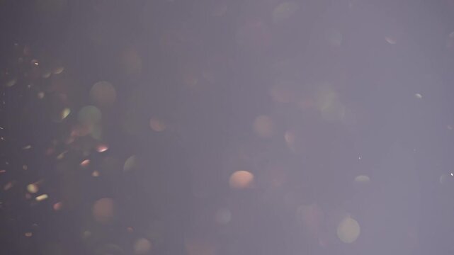 Soft blurred bokeh lights float against a gradient peach and gray background. Concept for overlay, holiday, events industries, beauty and cosmetics, branding, digital design, advertising and wallpaper