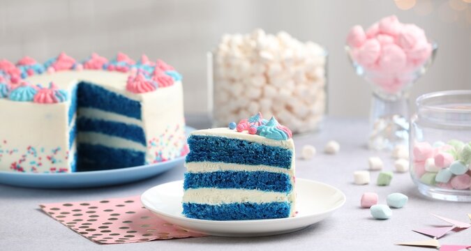 Slice of gender reveal cake with blue layers on light table, closeup