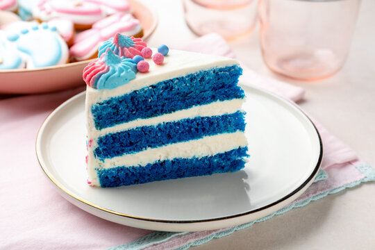 Slice of gender reveal cake with blue layers on light table, closeup