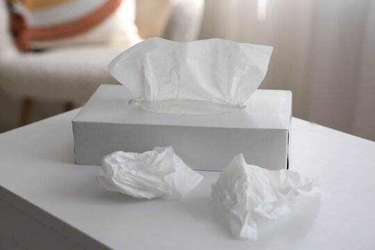 Box of paper tissues and used napkins on white table indoors