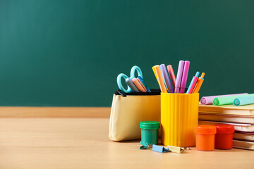 Different stationery on wooden table near chalkboard. Space for text © New Africa