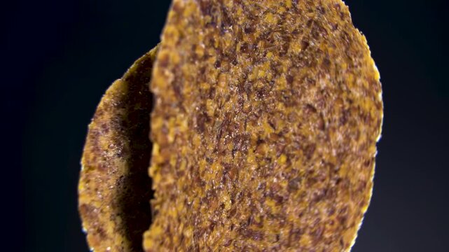 Round Fruit and Seed Crisp Rotating on Black Background, Close-Up