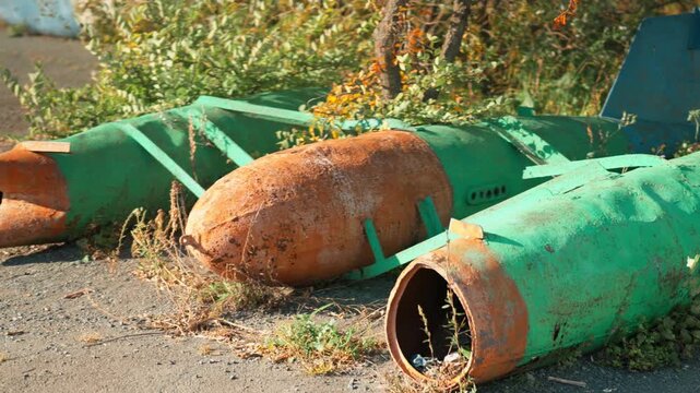 Obsolete, abandoned, and rusty combat missiles and shells stand amidst the natural landscape. A weapons graveyard. An echo of war.