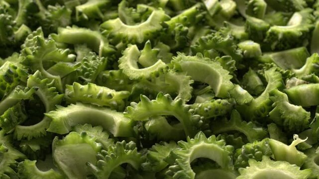 Close-up view of rotating bitter melon chunks, full-frame background texture. Bitter melon prepared for cooking, selective focus. 