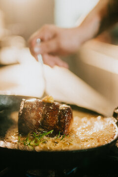 Chef adds finishing touches to a perfectly seared steak in a pan